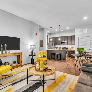 Open-concept living room with yellow accent furniture flows into a kitchen and dining area.